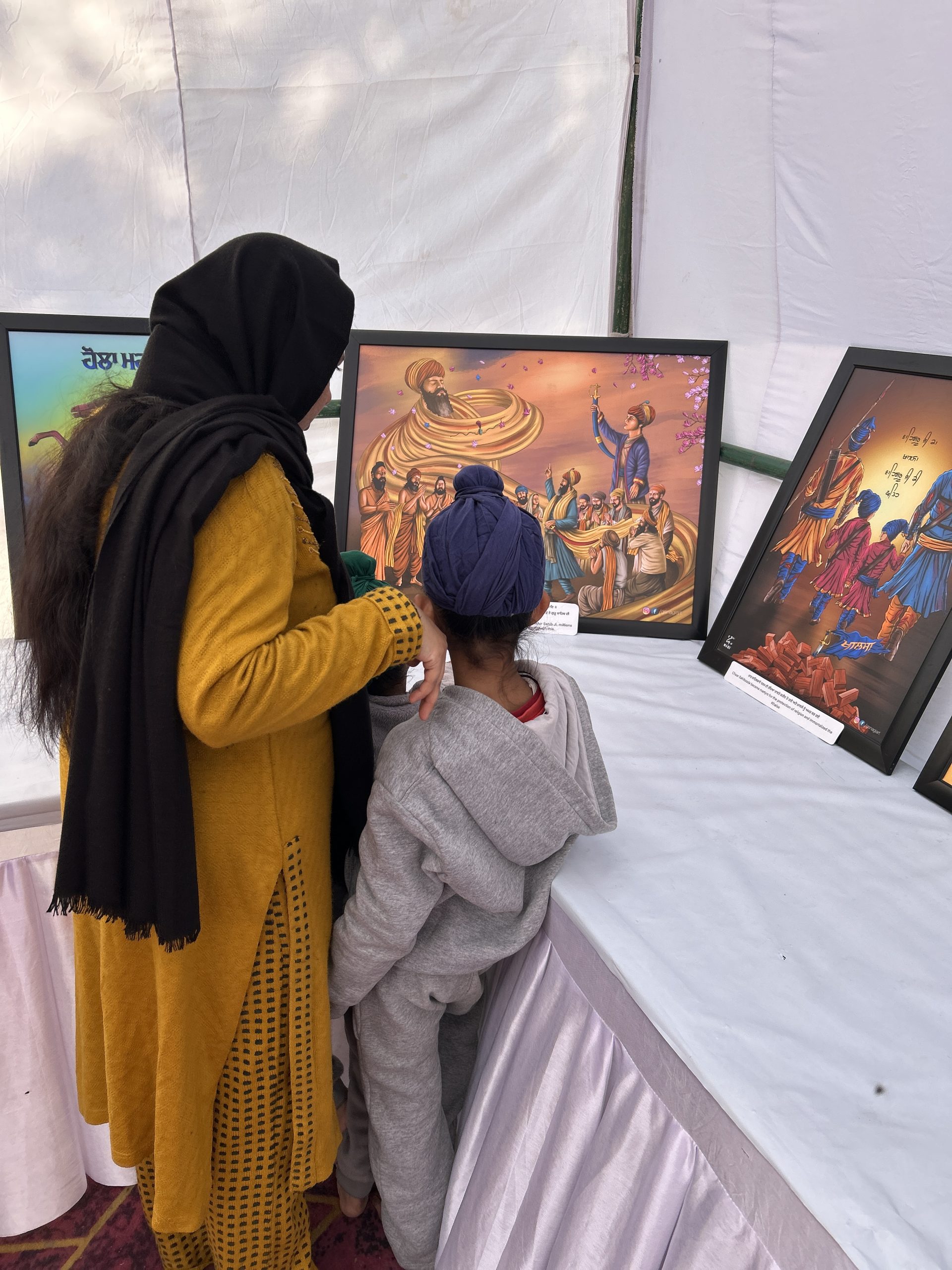 A mother and child looking at Sikh history artworks