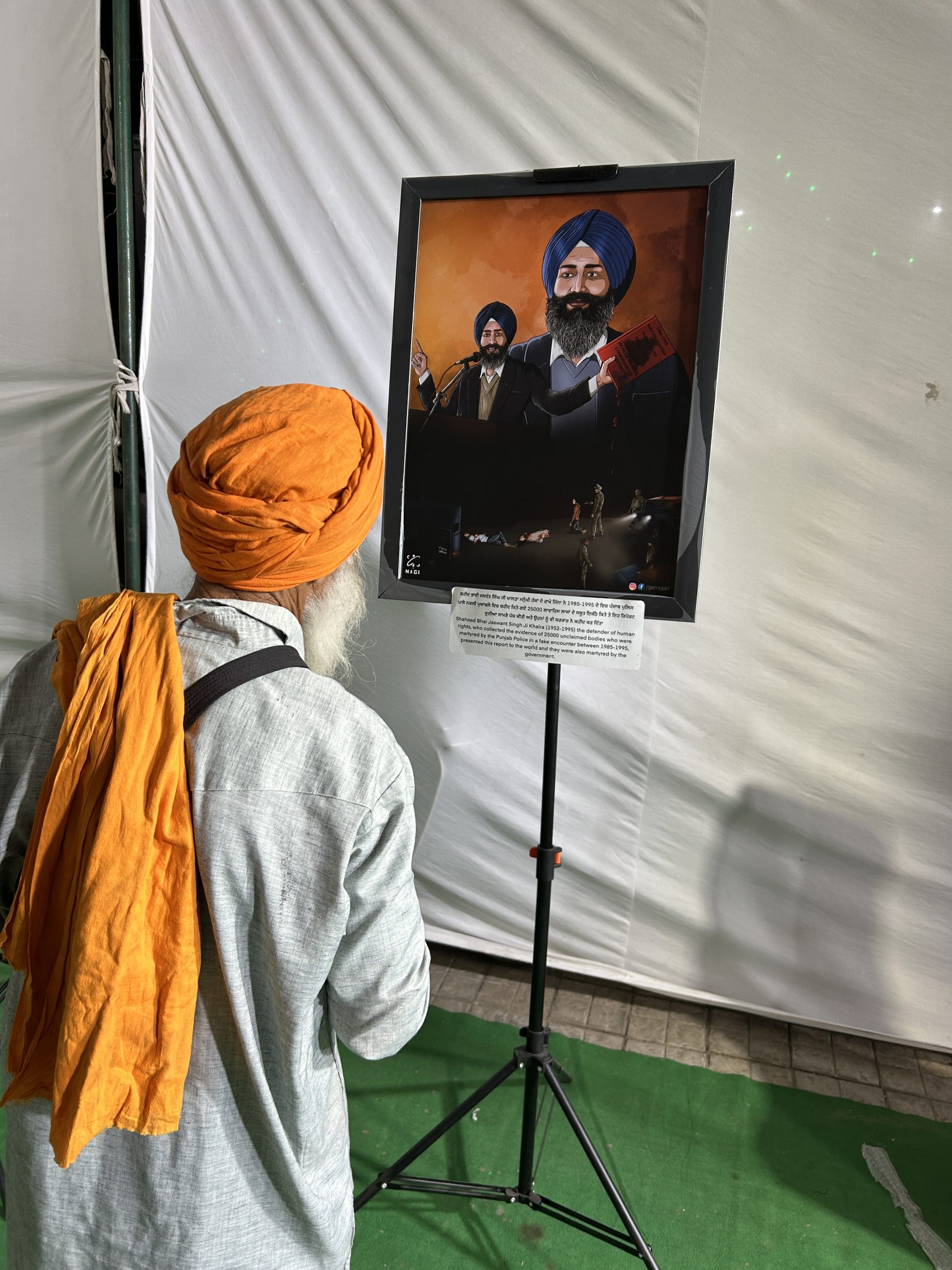 An elder reading the Punjabi caption beside a framed artwork