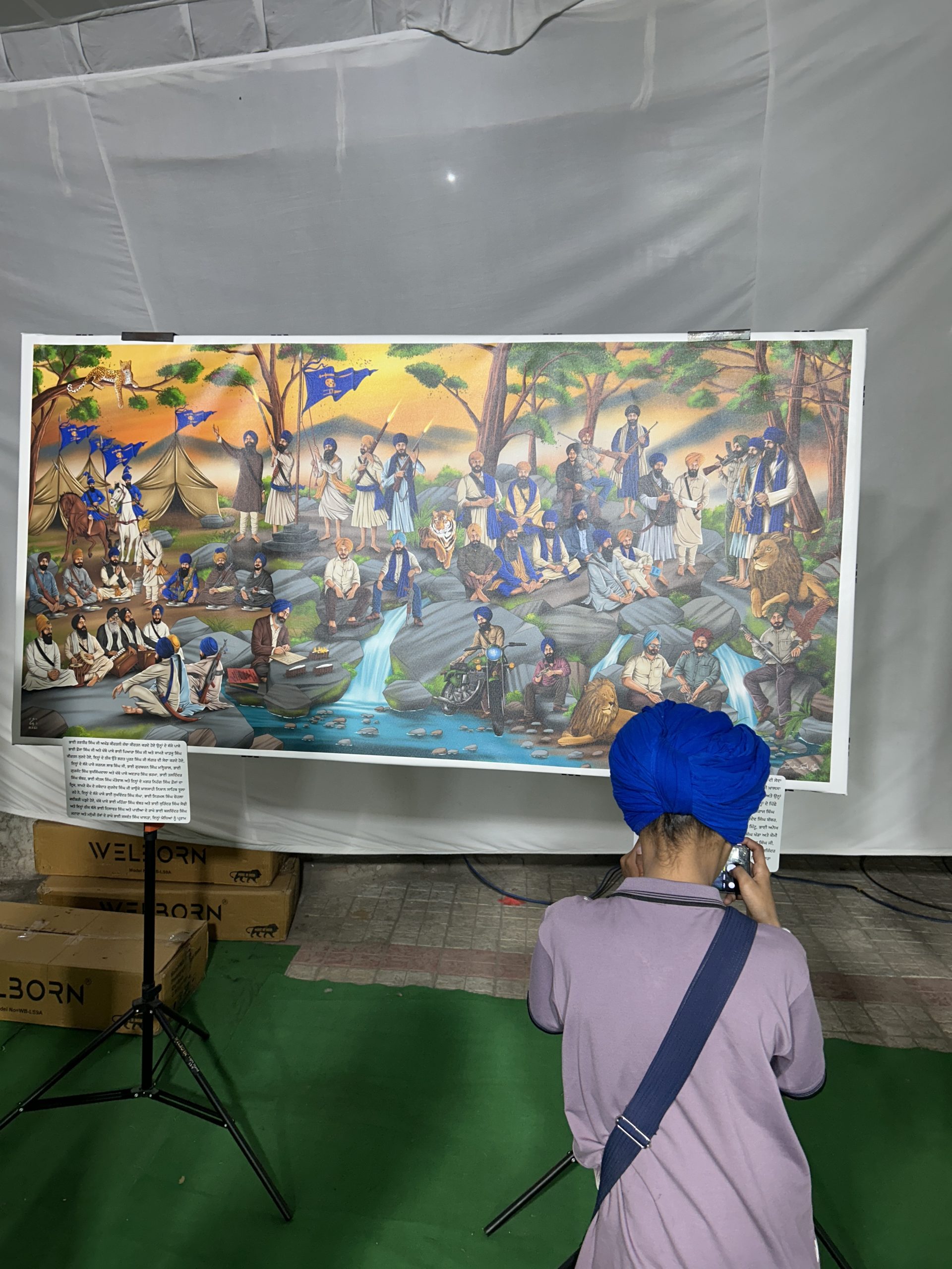 A visitor photographing a large Sikh history artwork