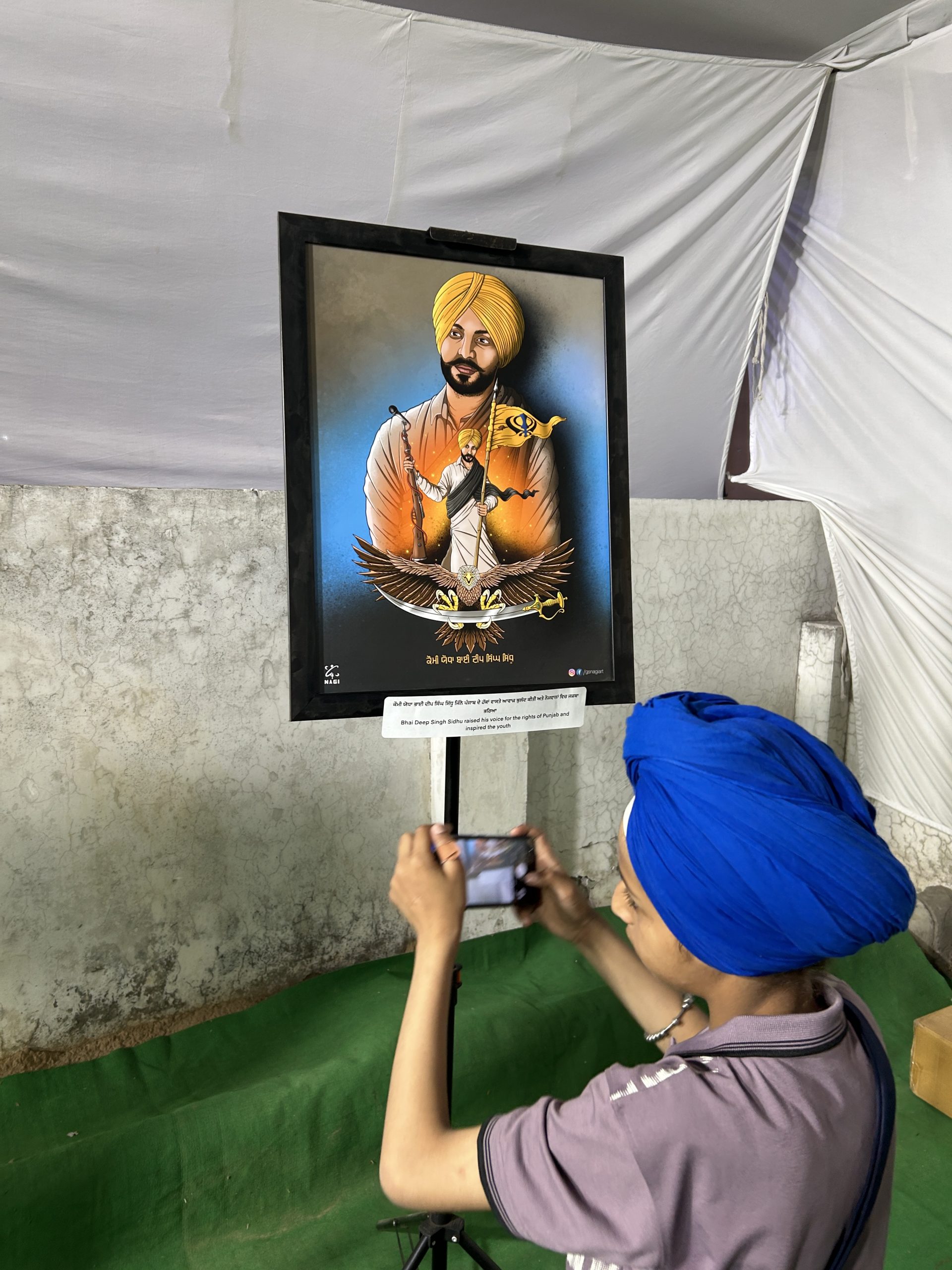 A young visitor photographing a framed Sikh artwork