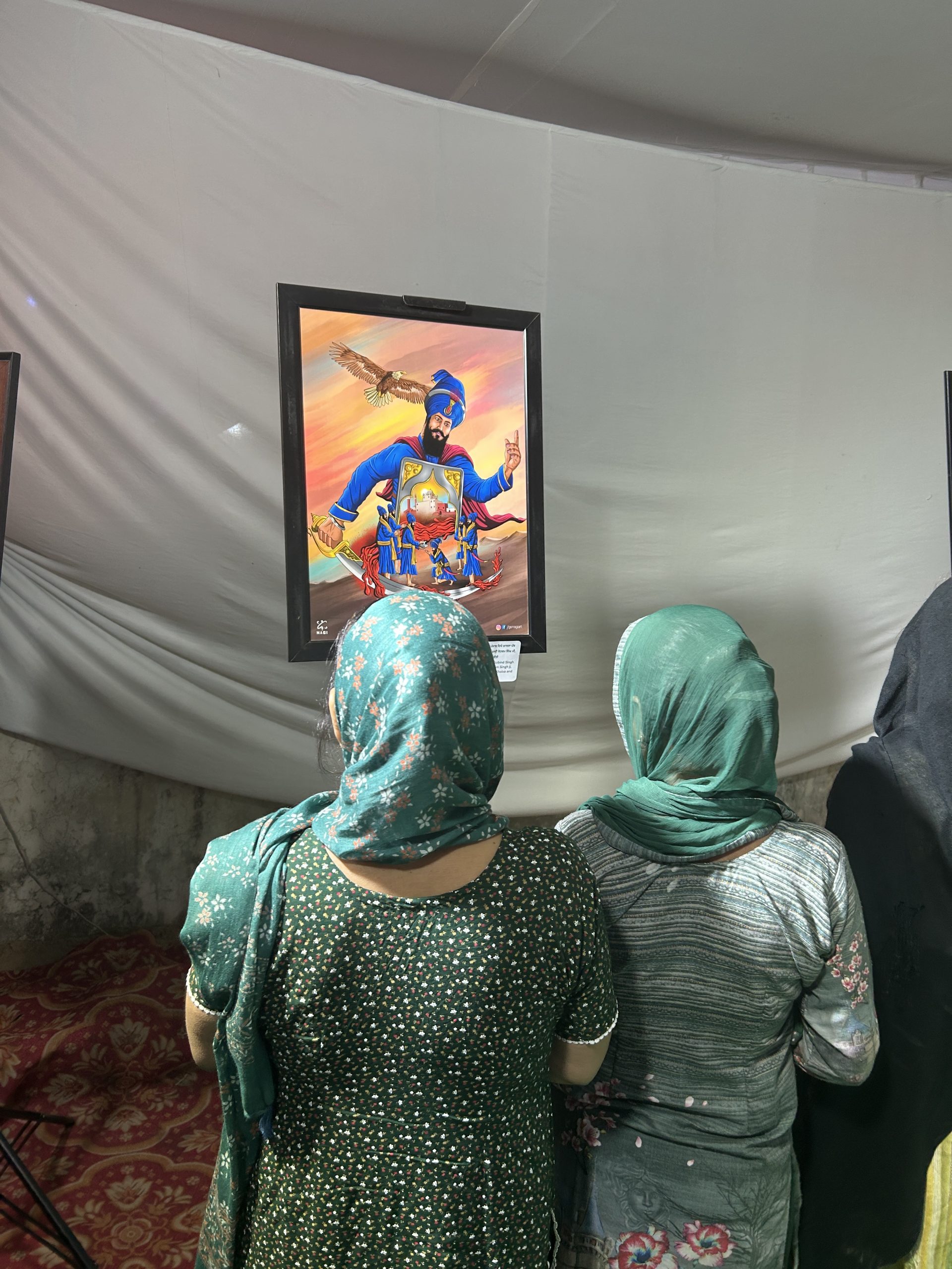 Visitors before a framed Guru Gobind Singh Ji artwork